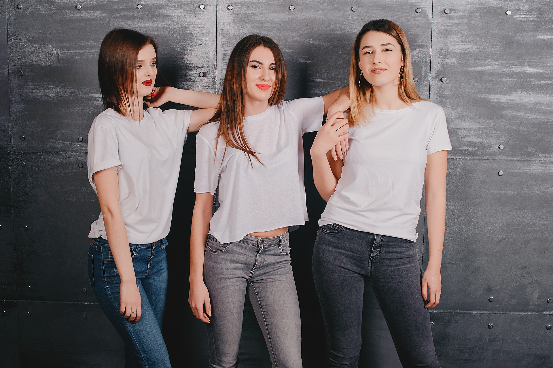 Beautiful three girls in a photo studio. Ladies in a white t-shirts
